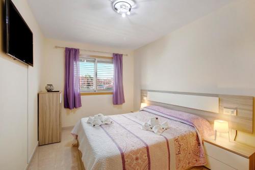 厄尔梅达诺La Perla D14 en el Médano的一间卧室配有一张大床和紫色窗帘