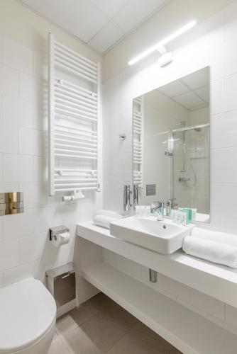 格但斯克Dom Zdrojowy的一间带水槽、卫生间和镜子的浴室