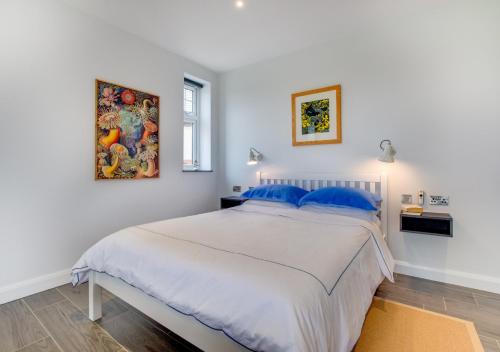 阿贝达隆Morannedd的白色卧室配有一张带蓝色枕头的大床