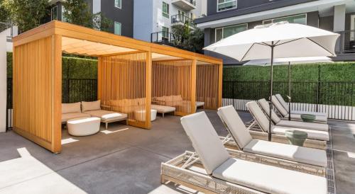 洛杉矶Modern Apartment Rentals的庭院设有带椅子和遮阳伞的凉亭。