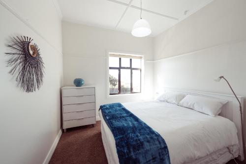但尼丁埃斯普耐德滨海公寓的白色的卧室设有一张大床和一个窗户