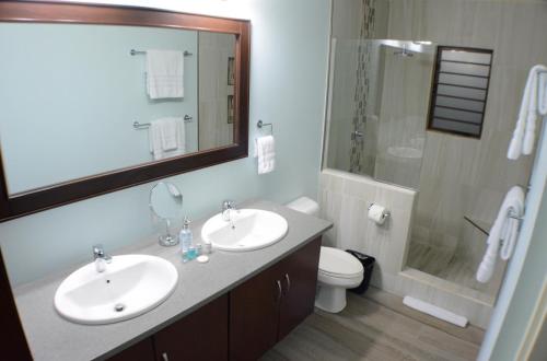 Boissiere VillagePen Manor Modern 2 Bedroom Apartment的一间带两个盥洗盆、淋浴和卫生间的浴室