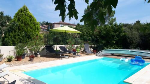 索尔格河畔利勒Villa avec piscine chez Raphaële的蓝色游泳池配有遮阳伞和椅子