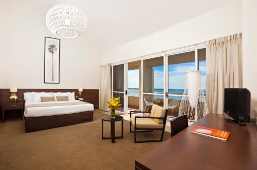 凯恩斯Cairns Harbourside Hotel的酒店客房配有一张床和一张书桌及一台电视