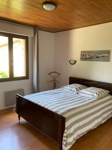 普卢贡旺Maison de campagne de plein pied.的一间卧室设有一张带木制天花板的大床
