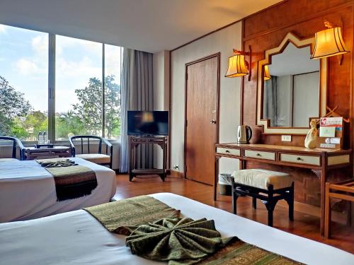 清迈Chiang Mai Orchid Hotel SHA EXTRA PLUS的酒店客房配有两张床和一张带镜子的书桌