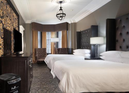 新奥尔良Le Pavillon New Orleans的酒店客房设有两张床和一台平面电视。
