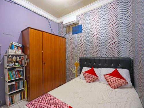名古屋OYO 91782 Satria Homestay Syariah的一间卧室配有一张带红色枕头的床和书架