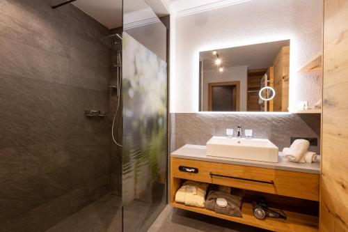 皮茨河谷圣莱昂哈德Hotel Mittagskogel Pitztal的一间带水槽和镜子的浴室