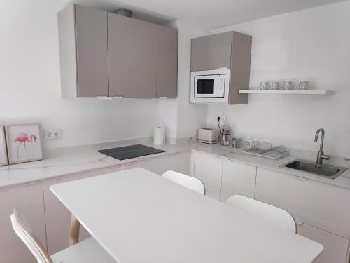 卢戈Apartamentos CANDEA的厨房配有白色橱柜和白色的桌椅