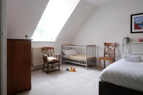 刘易斯Contemporary 2 Bedroom Flat in Lewes的一间卧室配有一张床、两把椅子和一张婴儿床