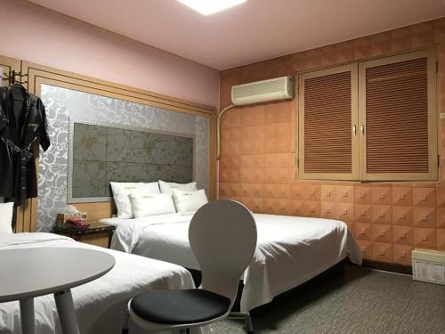 全州市Sharp Hotel Jeonju的酒店客房,配有两张床、一张桌子和一把椅子