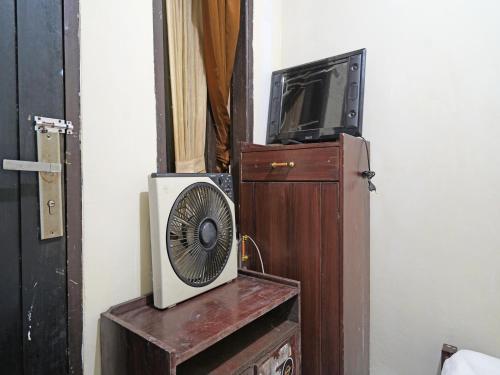万隆SPOT ON 91783 Urban Syariah Residence的木柜中的电视和风扇