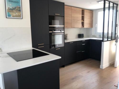 迪纳尔Vue mer exceptionnelle的厨房配有黑色橱柜和白色台面