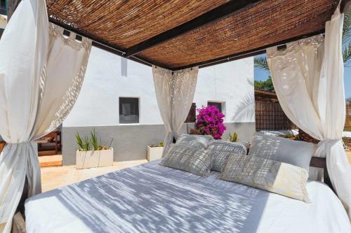 圣乔治Cas Catalá Sant Jordi的一间卧室配有一张带白色窗帘和紫色鲜花的床。