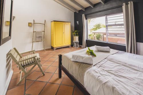 开普敦Cape Town Surf Hostel & Lodge的卧室配有床、椅子和窗户。