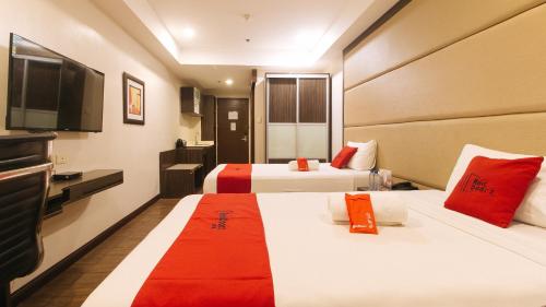 马尼拉RedDoorz Premium @ West Avenue Quezon City的酒店客房设有两张床和一台平面电视。