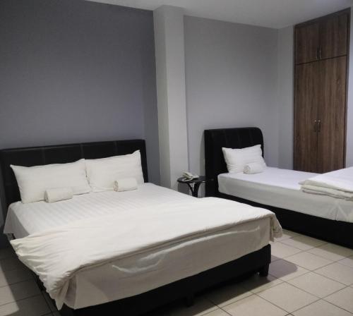 怡保Reintree Lodge Hotel的一间卧室配有两张带白色枕头的床