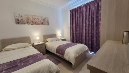圣保罗湾城Lovely Apartment with Side Sea View的一间卧室设有两张床和一个带紫色窗帘的窗户。