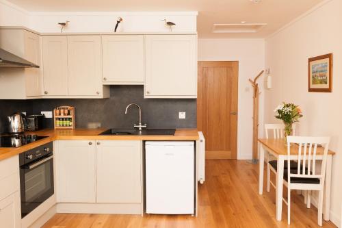 HallinAn Cala Beag Self Catering apartment on The Waternish Peninsula的厨房配有白色橱柜和木桌