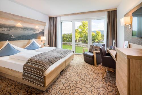 沃尔特湖畔佩莎赫Seehotel Das JO的配有一张床和一张书桌的酒店客房