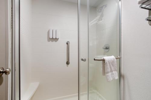 堪萨斯城Orangewood Inn & Suites Kansas City Airport的浴室里设有玻璃门淋浴