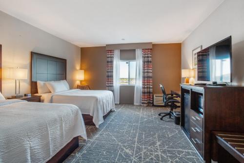 堪萨斯城Orangewood Inn & Suites Kansas City Airport的酒店客房设有两张床和电视。
