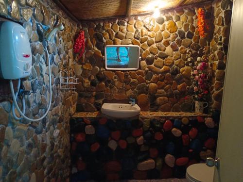 拜县sunny Tayai hostel pai的石质浴室设有水槽,墙上配有电视。
