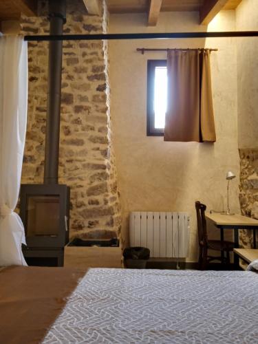 Alcudia de VeoCasa rural El Forn d'Alcudia de Veo的一间卧室配有一张床、一个壁炉和一张桌子