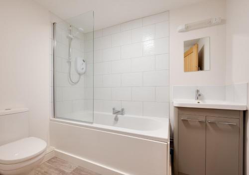 RingsteadJourneys End的白色的浴室设有浴缸、卫生间和水槽。