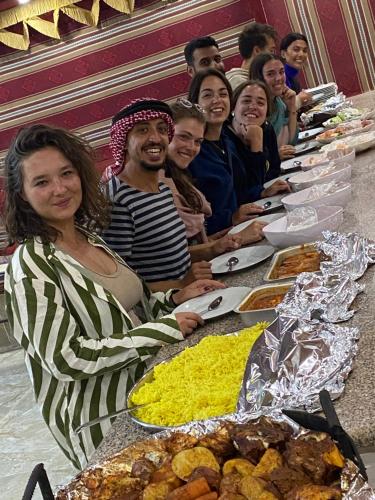 瓦迪拉姆Mountain Magic Camp Wadi Rum的一群人坐在长桌旁吃着食物