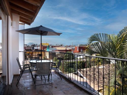 科阿特佩克Hotel Casa Real Del Café的阳台配有桌椅和遮阳伞。