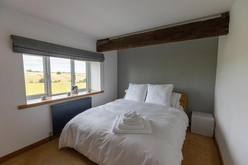 丹比戴尔BIRDS EDGE COTTAGE - Luxury 2 Bedroom Cottage with Amazing Views, Near Holmfirth in Yorkshire的卧室配有白色的床和窗户