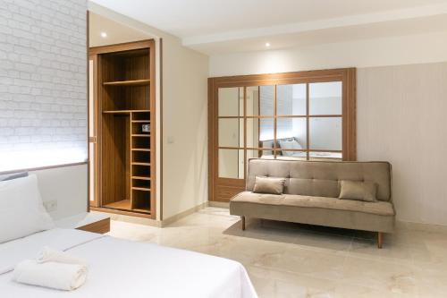 卡姆布库Hotel de Luxo Tango Suites & Coworking Cumbuco的一间卧室配有一张床、一张沙发和一个窗口