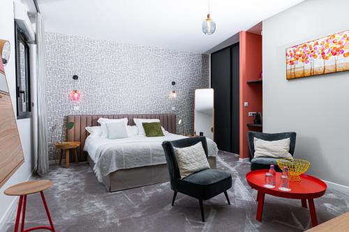 Aureville恩马基酒店的酒店客房带一张床、一张桌子和椅子