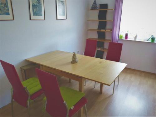 蒂宾根Gästezimmer Gross的一间带木桌和红色椅子的用餐室