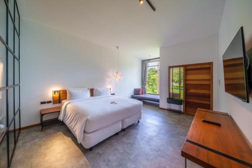 沙美岛班普罗海酒店的卧室配有白色的床和木桌