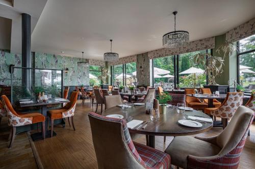 布罗肯赫斯特Forest Park Country Hotel & Inn, Brockenhurst, New Forest, Hampshire的餐厅设有桌椅和窗户。