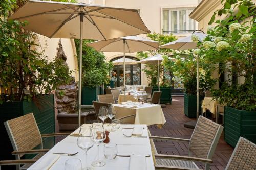 巴黎卢浮宫里贾纳酒店的一间带桌椅和遮阳伞的餐厅