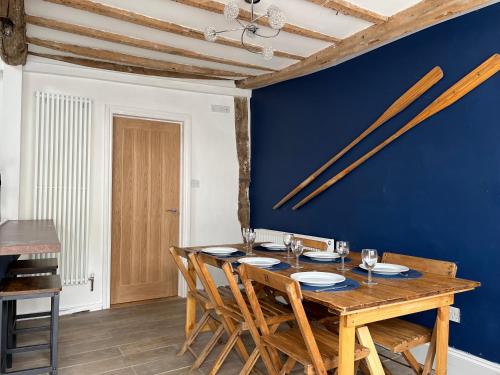 TillinghamLime Tree Cottage的一间设有木桌和蓝色墙壁的用餐室