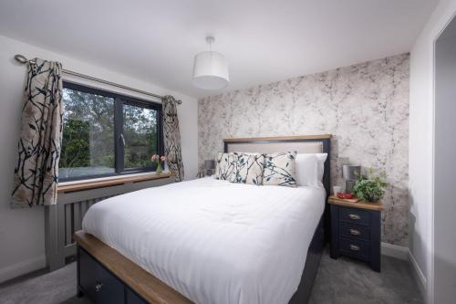 利夫顿Maple Lodge, 20 Roadford Lake Lodges的一间卧室设有一张大床和一个窗户。
