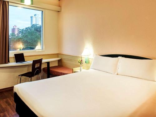 圣安德雷ibis Santo Andre的配有一张床、一张书桌和一扇窗户的酒店客房
