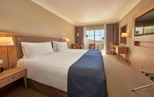 丰沙尔Hotel Porto Santa Maria - PortoBay - Adults Only的酒店客房设有一张大床和一张书桌。