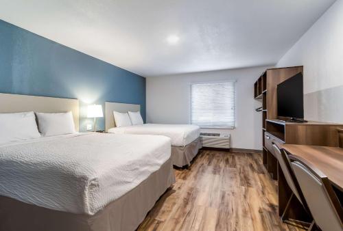 哈里斯堡WoodSpring Suites Harrisburg Linglestown的酒店客房设有两张床和一台平面电视。