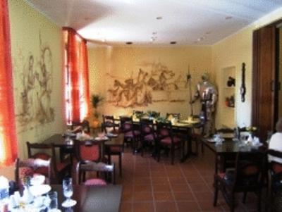 Bad Bodenteich祖姆阿尔腾里特餐厅酒店的餐厅设有桌椅,墙上挂有绘画作品