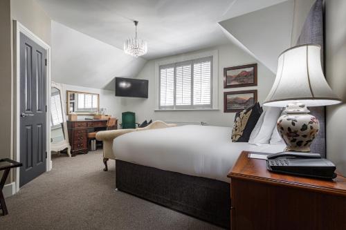布罗肯赫斯特Forest Park Country Hotel & Inn, Brockenhurst, New Forest, Hampshire的一间卧室配有一张床和一张带台灯的书桌