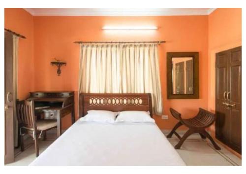 斋浦尔Magnolia Villa 4 BHK的一间卧室配有一张床、一张书桌和一个窗户。