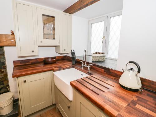 阿贝尔格莱Dove Cottage的厨房配有白色橱柜和木制台面