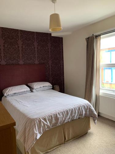WooltonLiverpool的一间卧室配有一张带红色床头板的床和窗户