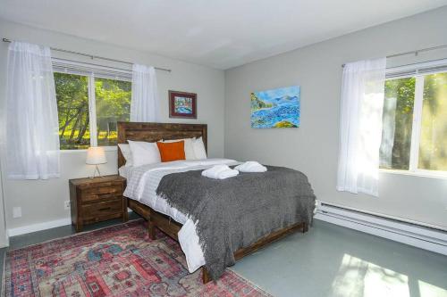 温哥华Adorable Cottage Among Trees Close To Everything的一间卧室设有一张床和两个窗户。